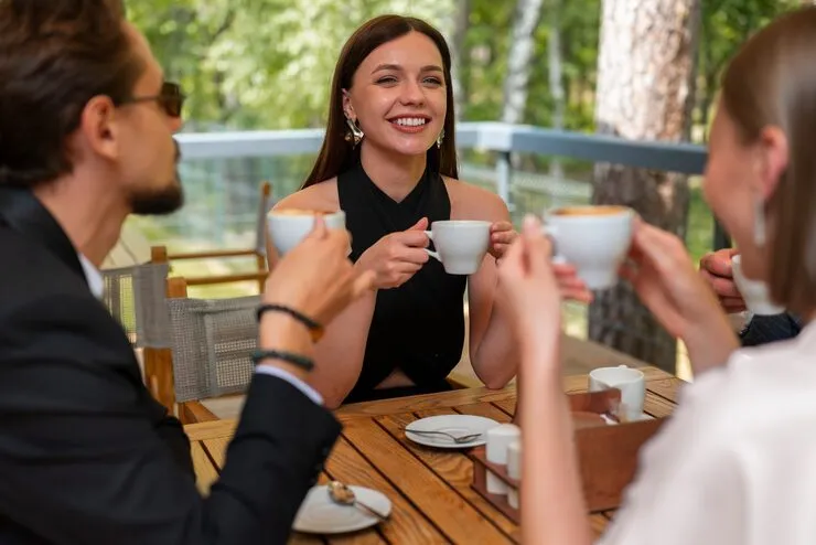Gruppe stößt an einem Café-Tisch mit Kaffeetassen an