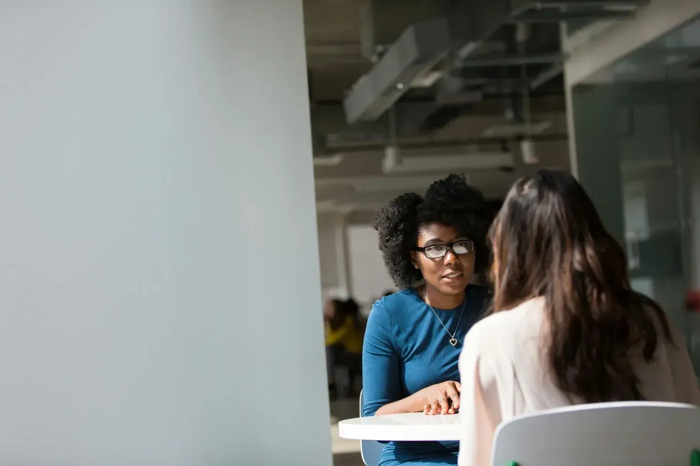 Zwei Frauen im Gespräch an einem Tisch im Büro